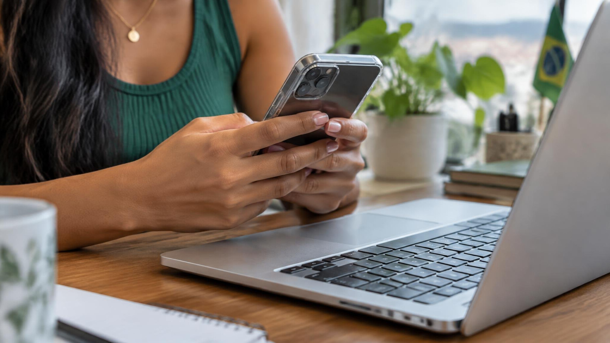 Hands holding a smartphone above a laptop keyboard
